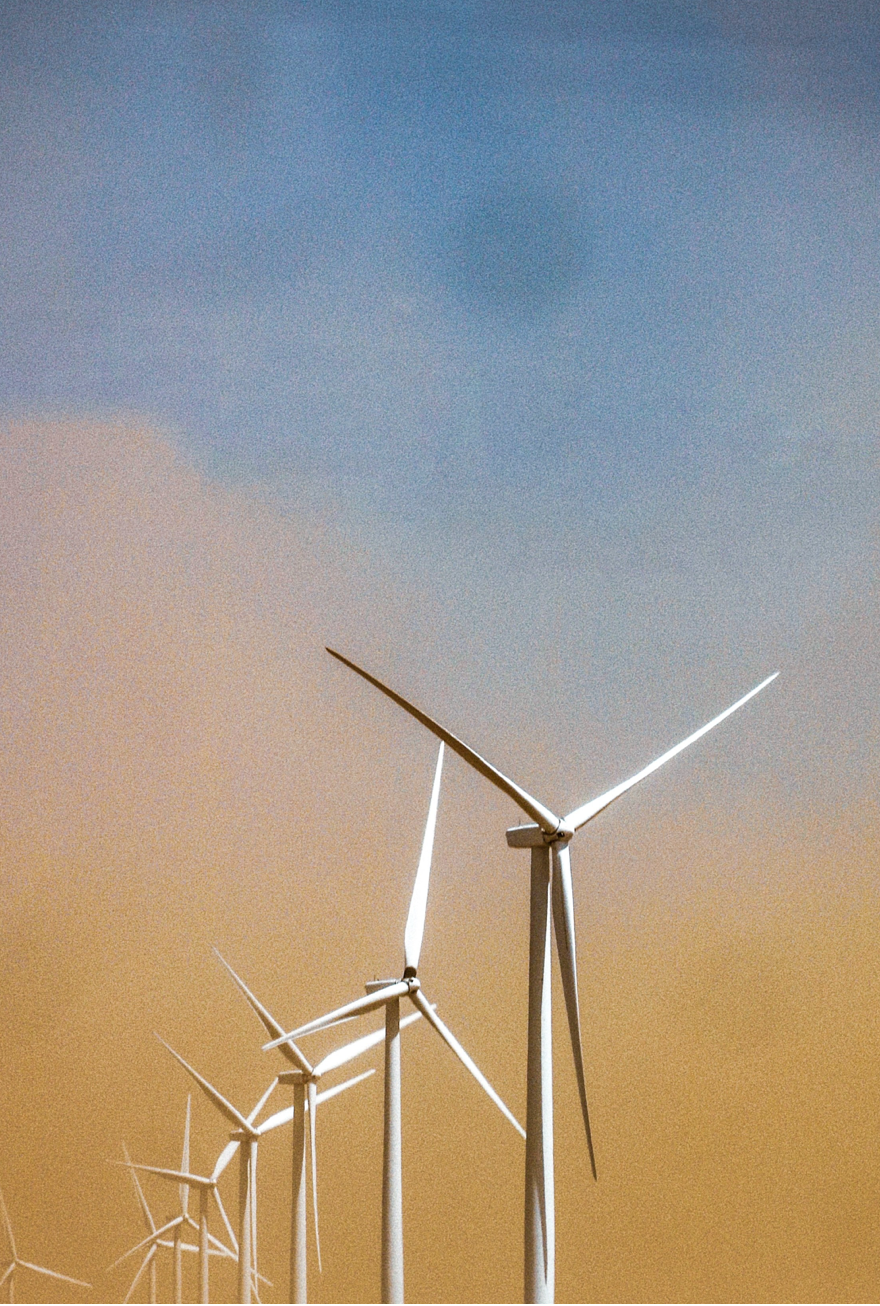 Wind turbines against an orange and blue sky.