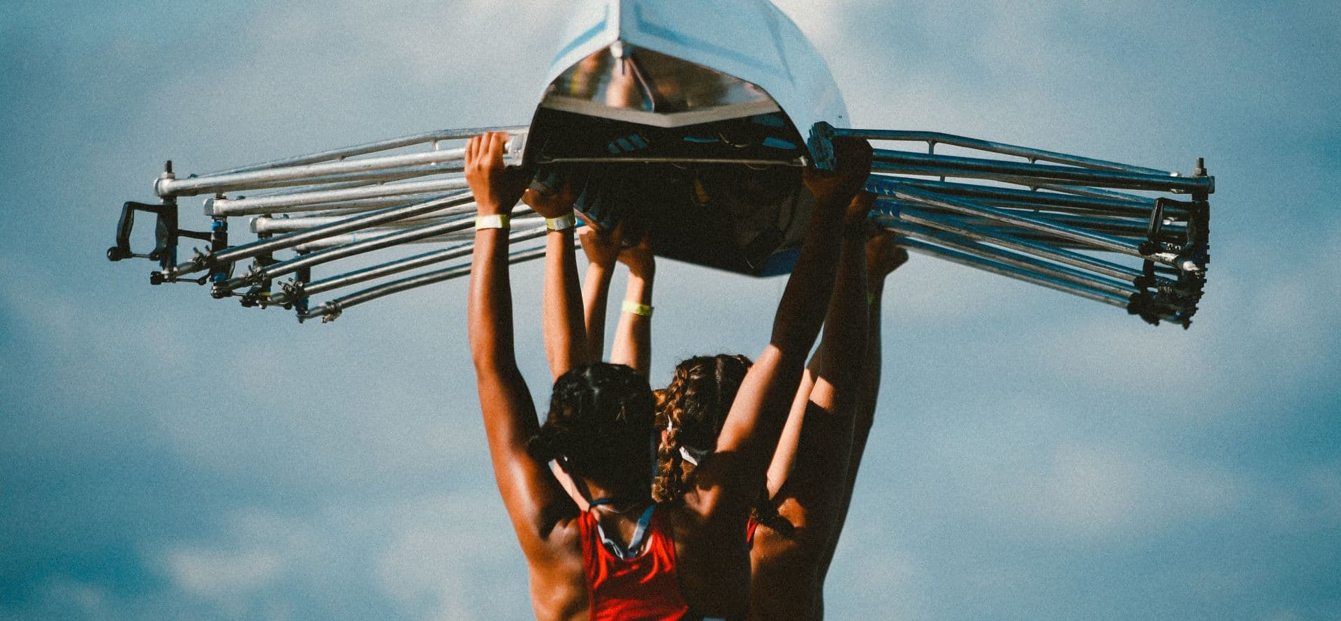A photograph of two rowers carrying a boat above their heads